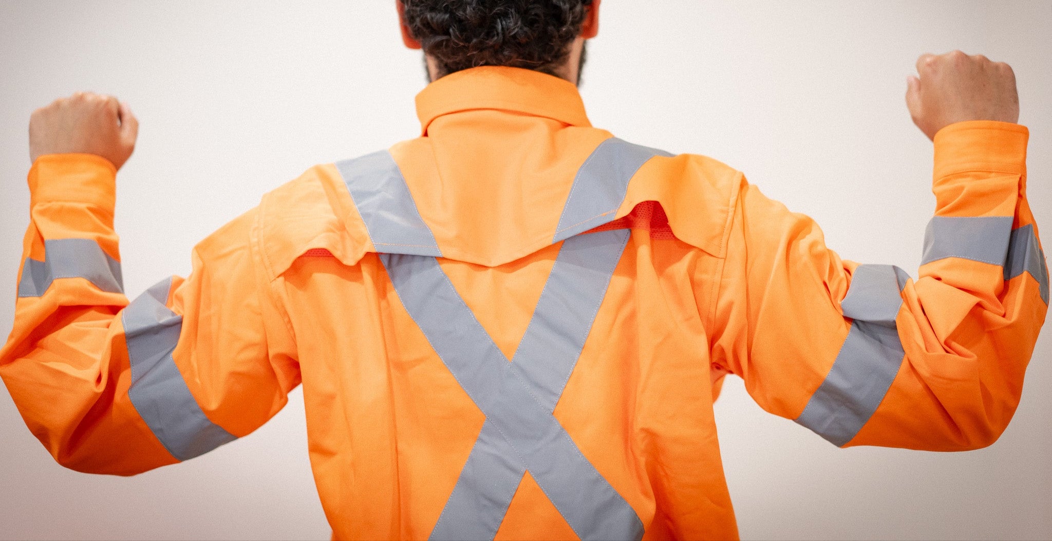 Person wearing an orange safety jacket with reflective stripes on a plain background